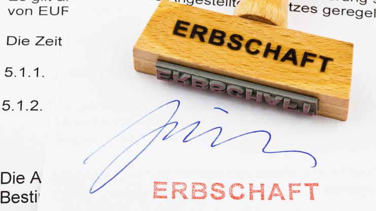 Holzstempel mit Aufschrift "ERBSCHAFT" auf einem Dokument, das eine Unterschrift und den Stempelabdruck zeigt.