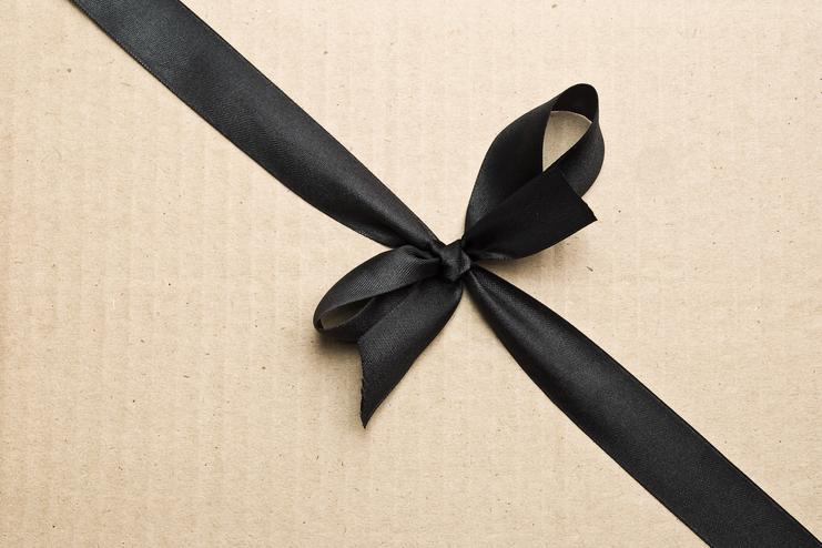 Schwarzes Satinband in einer Schleife auf einem braunen Papierkarton.