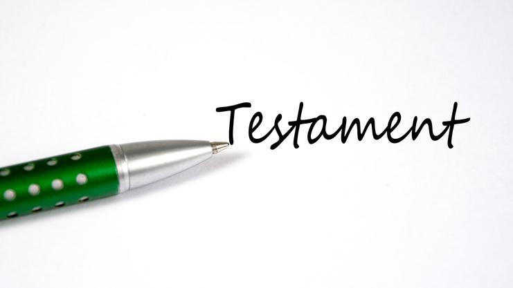 Grüner Kugelschreiber liegt neben dem handschriftlichen Wort „Testament“ auf weißem Papier.